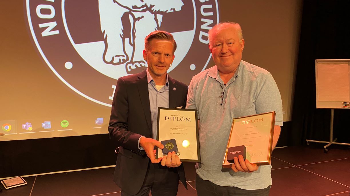 Ishockeypresident Tage Pettersen fikk æren av å dele ut både NIHFs gullmerke med diplom  og NIFs hederstegn til Jon Haukeland.